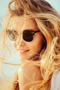 Beautiful blonde woman wearing sunglasses at the beach